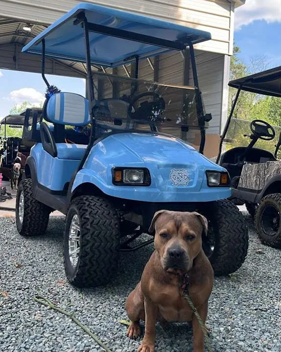 A lifted golf cart Andy worked on, with a dog sitting in front of it