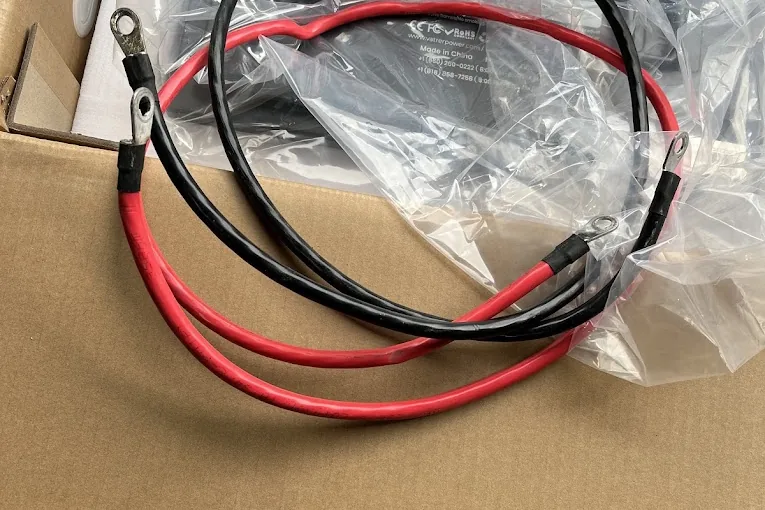 Battery cables and a charger laid out before a golf cart repair